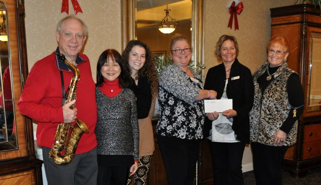Musicians and organization representatives pose for photo with a check