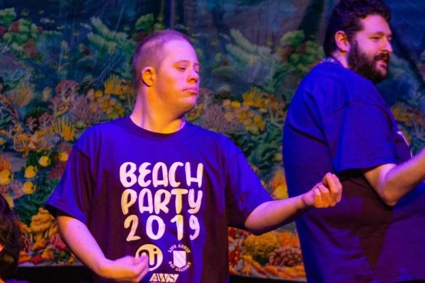 L.I.F.E. Adult Day Academy students play air guitar on stage