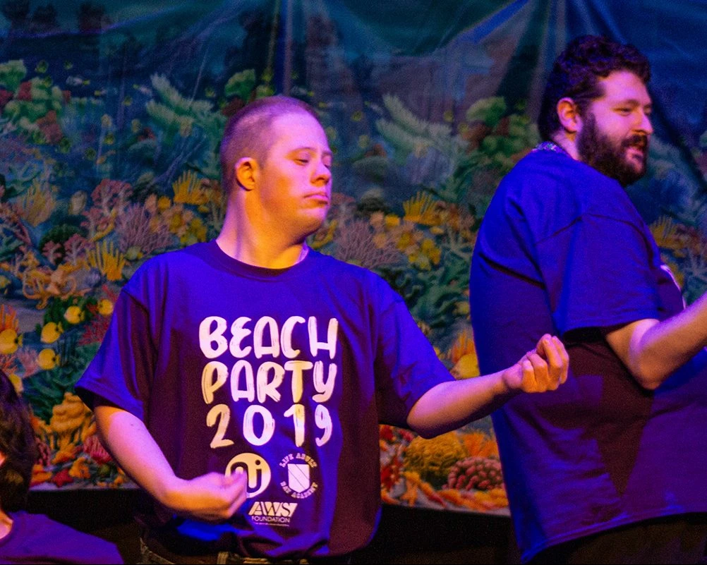 L.I.F.E. Adult Day Academy students play air guitar on stage